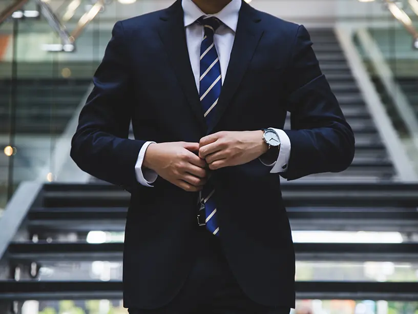 En mand i jakkesæt justerer sit slips.