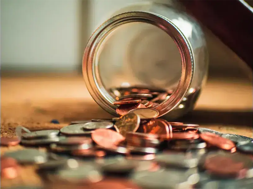 En krukke fuld af mønter på et bord.
